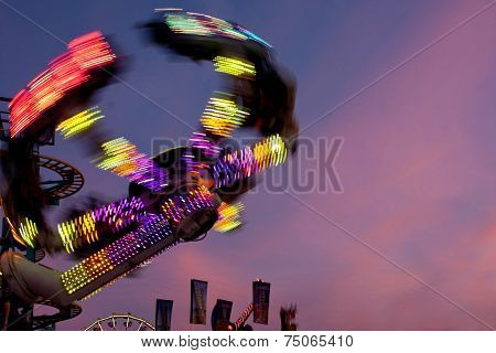 Colorful Lights Of Carnival Ride Motion Blur At Dusk