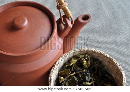 Teiera di argilla e cesto di foglie di tè