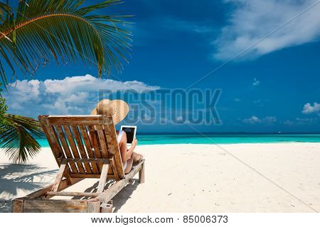 Young woman in hat with tablet pc at the beach