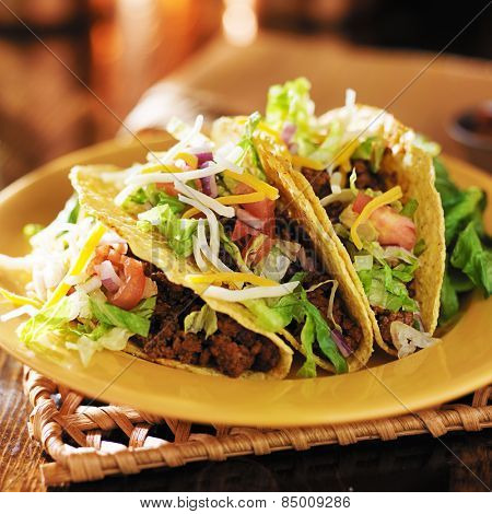 three beef mexican tacos with cheese and lettuce