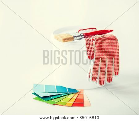 interior design and home renovation concept - paintbrush, paint pot, gloves and pantone samplers