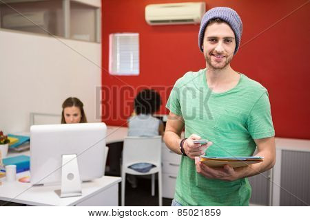 Portrait of handsome young casual businessman text messaging in office