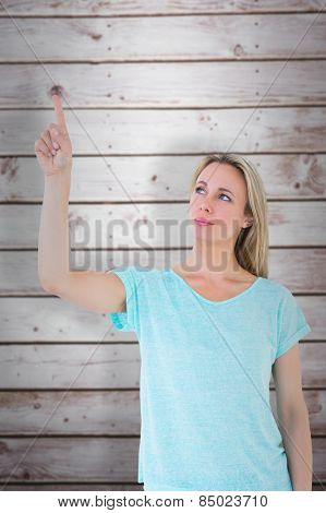 Pretty blonde thinking and pointing up against wooden planks
