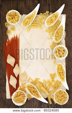 Pasta selection and tomato spaghetti food abstract forming a border over old parchment and oak background.