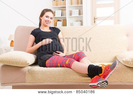 Young pregnant woman resting after doing finess at home
