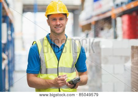 Worker using hand held computer in warehouse