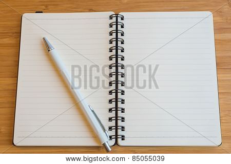 Note book and pencil on the wooden table.