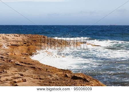 The Waves Beat Against The Rocky Shore. Water Flooded Depressions In The Rocks. Malta, Saint Julians