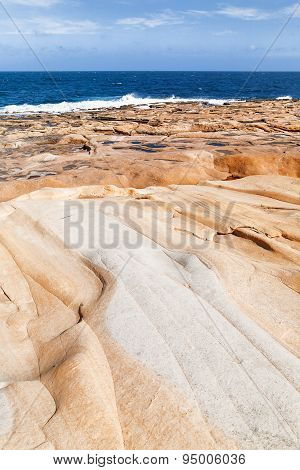 The Waves Beat Against The Rocky Shore. Water Flooded Depressions In The Rocks. Malta, Saint Julians