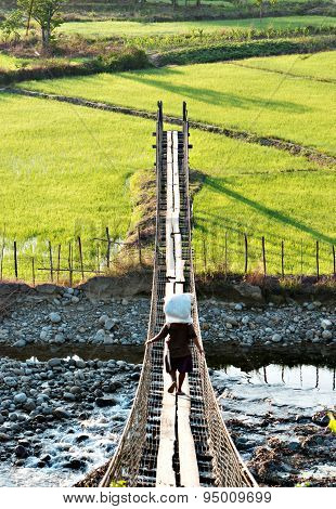 Villager Of Kampung Togudon Carrying A Sack Of Fertilizer On A Suspension Bridge To Go To His Paddy