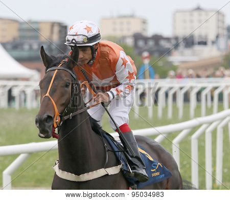 Man In Orange Clothes Riding A Race Horse