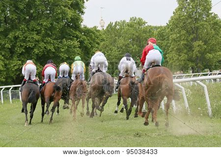 Rear View Of The Race Horses In A Curve