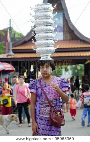 Mon girl carries pots on her head