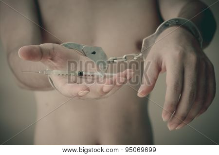 Young Man Holding Syringe In Hand With Handcuffs