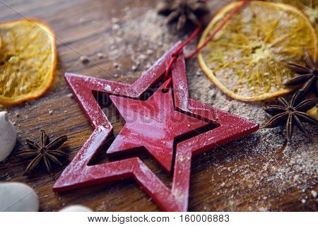 red wooden star lies with dried orange, cinnamon and meringue on wooden dark table