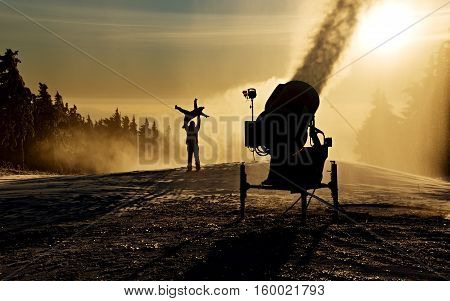 Father is playing with his children next to the snow cannon.