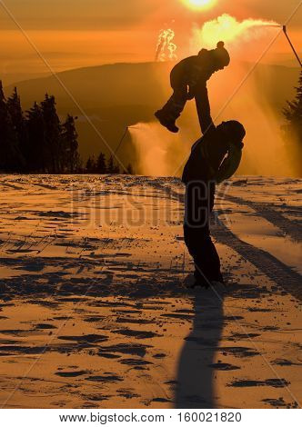 Father is playing with his children next to the snow cannon.