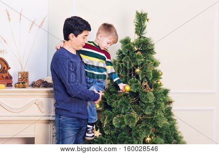 Father and son are decorating the Christmas tree.