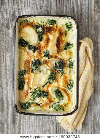 close up of rustic golden spinach potato gratin dauphinois