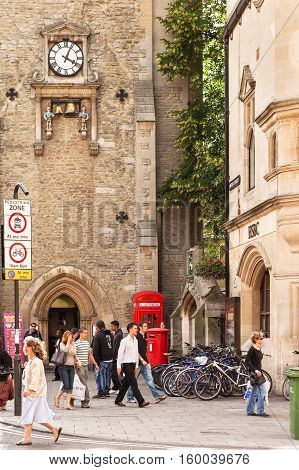 Oxford United Kingdom - June 20 2006: St Martin's Tower (Carfax Tower) with a clock that chimes the quarter hours on a pair of bells. K2 red telephone kiosk and post box beside St Martin's tower with bicycle parking. People of various ages walking shoppin
