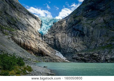 Briksdalsbreen glacier view, lightened by sun beam. Popular touristic hiking destination. Briksdal, Norway.