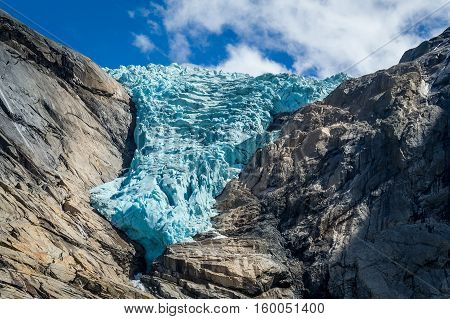 Close view of Briksdalsbreen glacier, turquoise ancient ice in the rocky mountains. Briksdal, Norway.