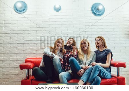 Beautiful girls sitting on the couch, have fun and make selfie Hostel
