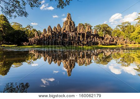 Angkor wat temple reflecting in a glassy lake