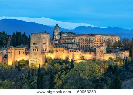 Alhambra - medieval Moorish fortress surrounded by yellow autumn trees illuminated in the evening Granada Andalusia Spain
