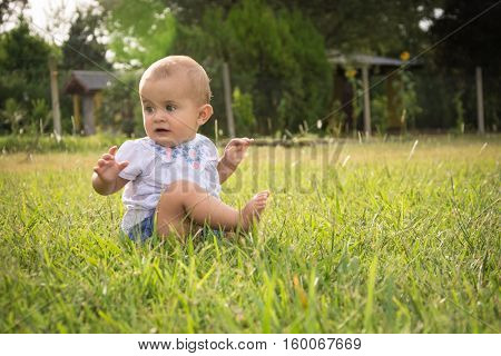 happy young baby child sittng on grass on beautiful summer day in park
