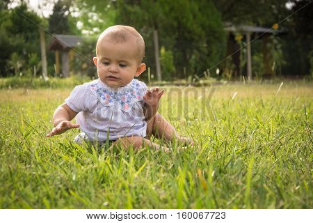 happy young baby child sittng on grass on beautiful summer day in park