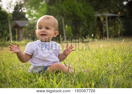 happy young baby child sittng on grass on beautiful summer day in park