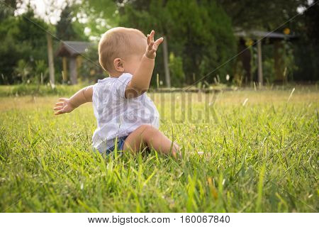happy young baby child sittng on grass on beautiful summer day in park