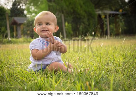 happy young baby child sittng on grass on beautiful summer day in park
