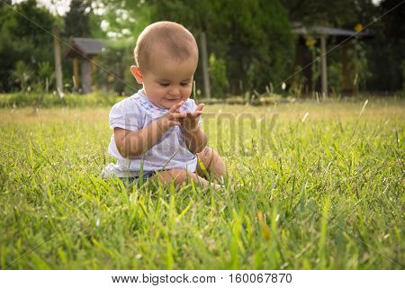 happy young baby child sittng on grass on beautiful summer day in park