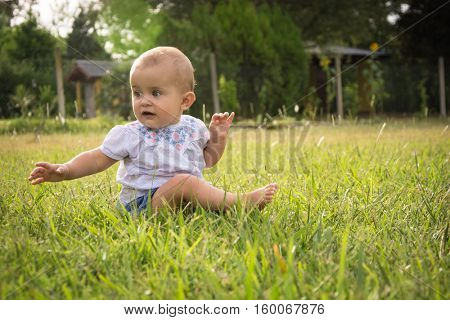 happy young baby child sittng on grass on beautiful summer day in park