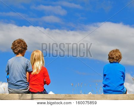 Three kids sitting over the blue sky