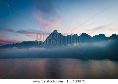 Romantic sunset over the lake in the Swiss Alps. In the background the mountains silhouettes.