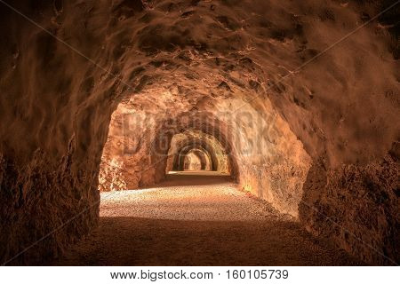 Тunnel in the mountain with a footpath stretching into the distance. Diminishing perspective. Interesting structure and color of the stone.