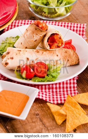 Tortilla wraps with chicken and vegetable on white dish.