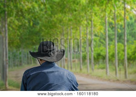 Man wearing jean jecket and black hat standing look background of trees.
