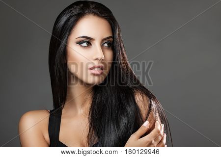 Portrait attractive brunette on a gray background. Beautiful dark hair. Girl looking away