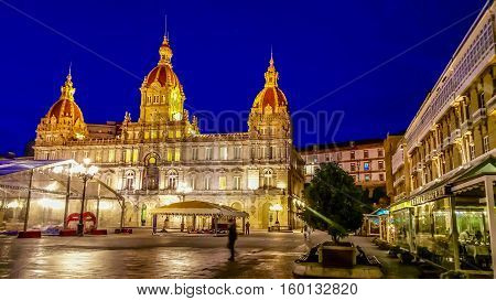 Night cityscape of La Coruna, Galicia, Spain. Illuminated Municipal Palace and City Hall Square of La Coruna at blue evening hour