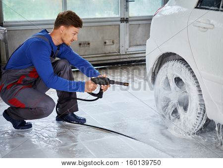 Man worker washing luxury car on a car wash.