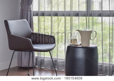 Ceramic Coffee Set On The Table With Black Leather Easy Chair In Living Room