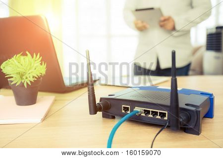 closeup of a wireless router and a man using Tablet on living room at home ofiice
