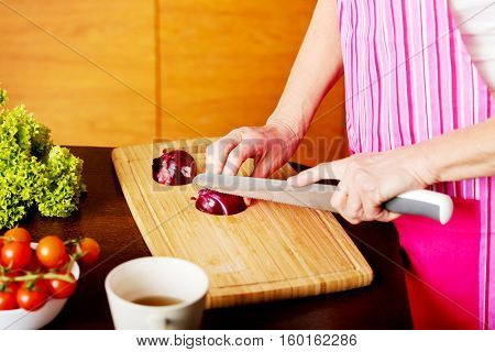 Woman cut red onion on cutting board