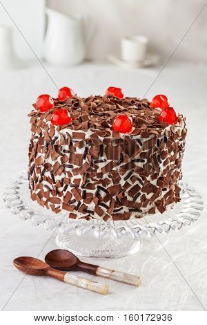 Black forest cake with cherries on a cake stand.