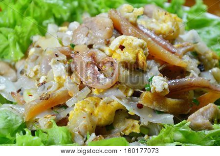 stir fried rice noodle with chicken and crispy pickled squid on dish
