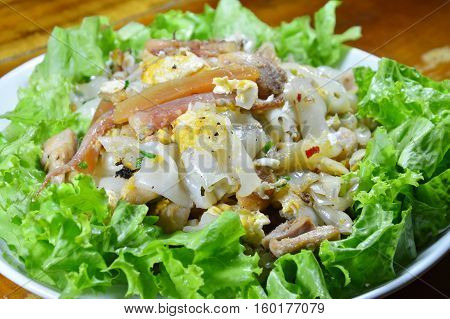 stir fried large noodle with chicken and crispy pickled squid on dish